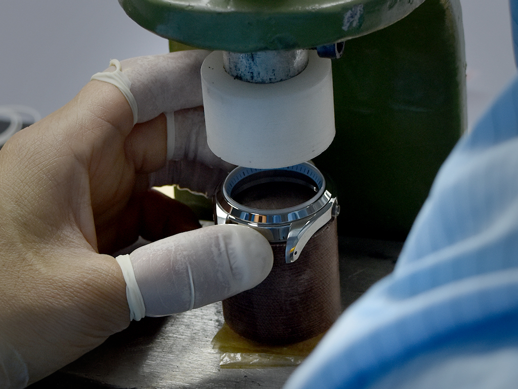 The watchmaker skifully insert the sapphire crystal into the case.
