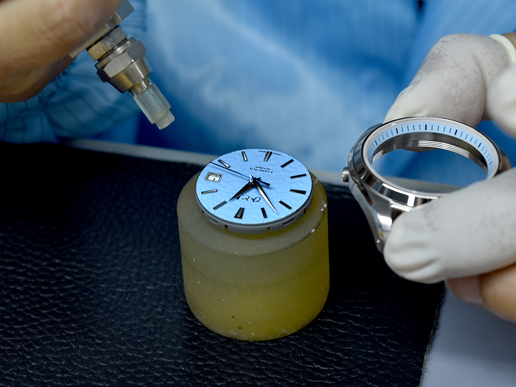 Double checking if there's any flaws or dust particles simultaneously before causing the dial and movement.
